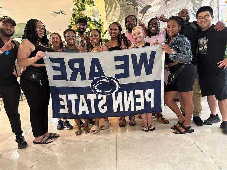 A group of people posing with a We Are Penn State sign